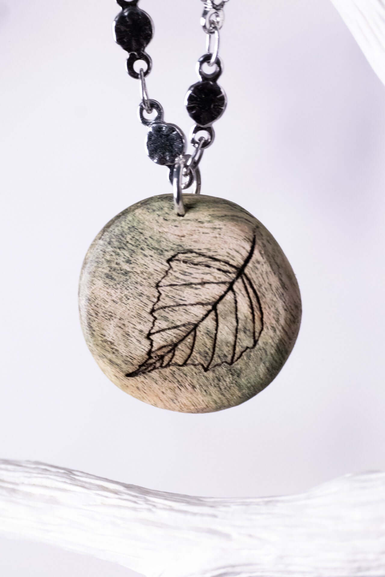 Frühlingserwachen Holzschmuck handgefertigt mit feiner Lasergravur eines Blattes in zarten Grüntönen.
